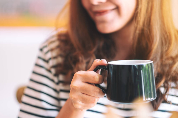 Closeup image of a beautiful woman holding a green cup of hot coffee to drink - Photo, Image
