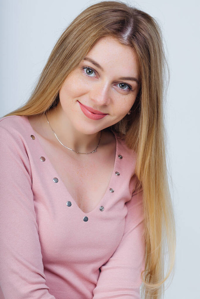 Portrait of happy girl with freckles smiling while looking at camera. wearing pink sweater with long hair - Zdjęcie, obraz