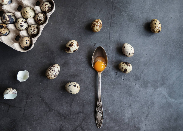 composition of quail eggs in eco-friendly packaging with a spoon with the yolk. The view from the top - Foto, Imagen