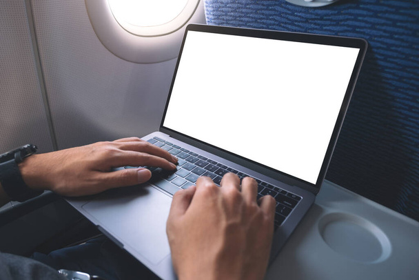 Mockup kép egy férfi használ és gépel laptop számítógép üres fehér asztali képernyő, miközben ül a kabinban - Fotó, kép