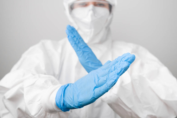 Doctor in a biohazard protective PPE suit and protective face mask fights with coronavirus, Sars-Cov-2, Covid-19 in blue rubber gloves. - Foto, immagini