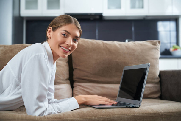 Beautiful woman lying on couch with wireless laptop - Foto, Bild