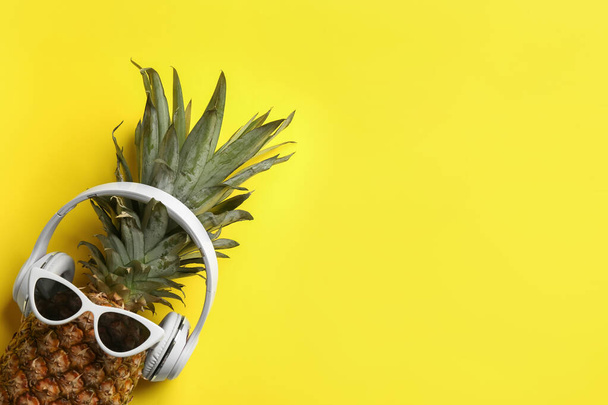 Top kilátás ananász napszemüveggel és fülhallgatóval sárga háttérrel, hely a szövegnek. Kreatív koncepció - Fotó, kép
