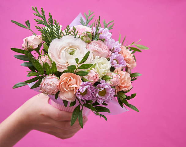 Beautiful bouquet of mixed different flowers in hand on pink background, greeting, gift - Photo, Image