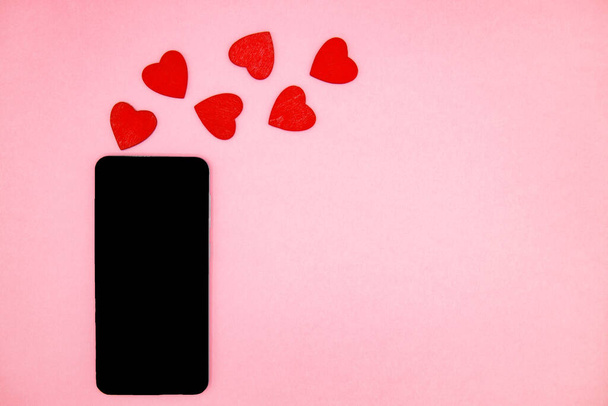 Mobiltelefon mit leerem Bildschirm und rotem Hörer auf rosa Hintergrund. Valentinstag-Konzept mit Platz für Text. Attrappe. Online-Nachricht. Glückwunsch im Internet. Lieferung, Online-Shopping - Foto, Bild