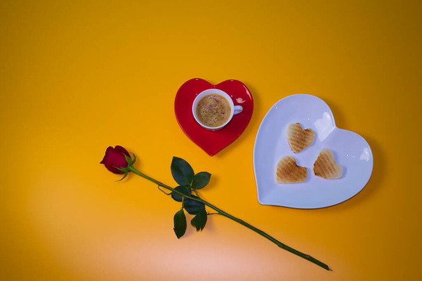 Café et pain grillé et rose naturelle sur fond noir pour le petit déjeuner le jour de la Saint-Valentin, plats rouges et blancs en forme de cœur. Vu de la position du zénith. - Photo, image