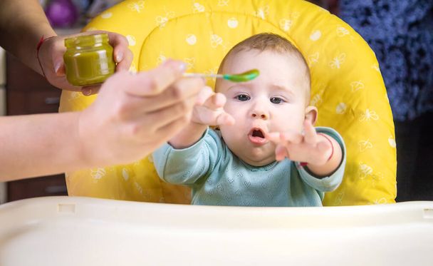 El pequeño bebé está comiendo puré de verduras de brócoli. Enfoque selectivo. Gente. - Foto, Imagen