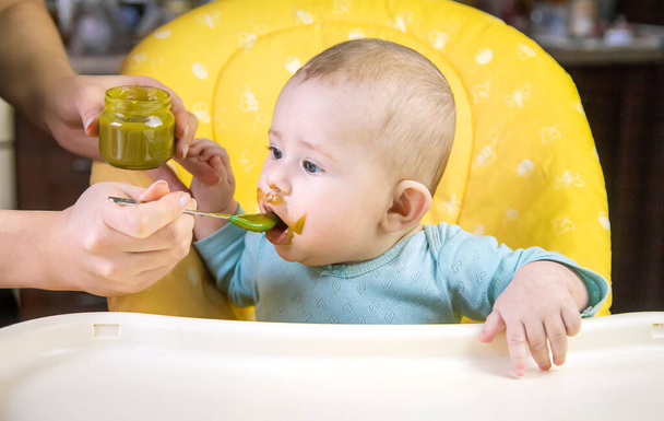 El pequeño bebé está comiendo puré de verduras de brócoli. Enfoque selectivo. Gente. - Foto, imagen