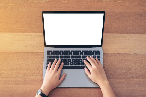 Imagem de maquete de vista superior de uma mulher usando e digitando no laptop com tela de desktop branca em branco na mesa de madeira no escritório - Foto, Imagem