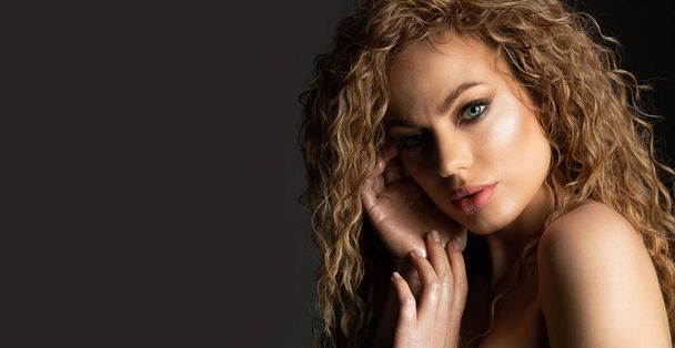 Closeup fashion portrait of an amazing young woman with curly hair posing at the grey wall. Space for text - Photo, Image