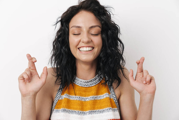 Pretty young happy positive woman isolated over white wall background showing hopeful crossed fingers gesture - Photo, Image