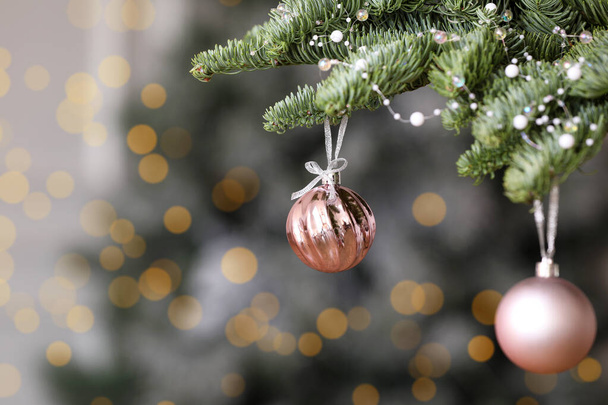 Pink Christmas balls hanging on fir tree against blurred background, space for text - Φωτογραφία, εικόνα