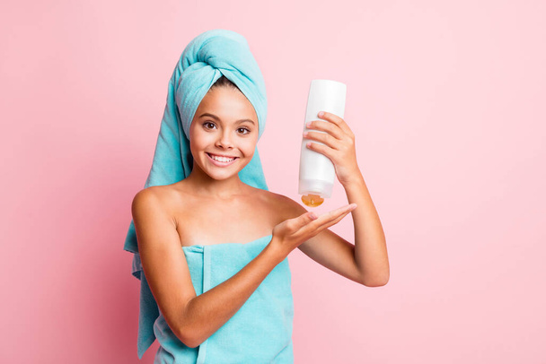 Portrait of sweet cheerful girl wear teal towel use conditioner isolated on pastel pink color background - Photo, image