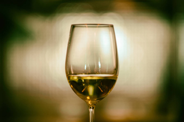 Closeup image of champagne in a wine glass with blurred light background - Photo, image