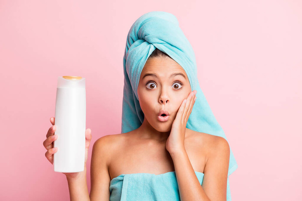 Portrait of pretty impressed girl wear teal towel show shower gel hand on cheek isolated on pastel pink background - 写真・画像