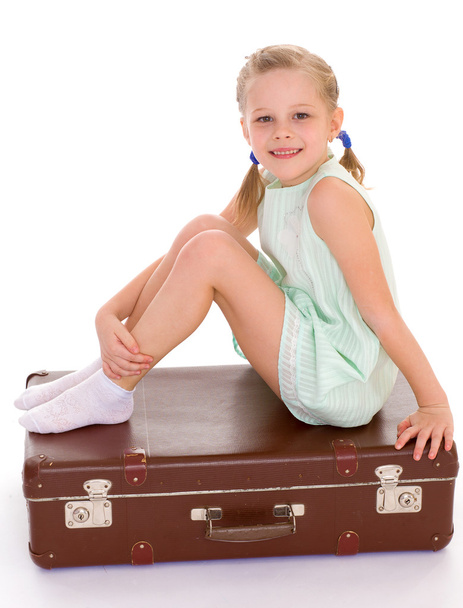  little girl with a big and very old suitcase. - Zdjęcie, obraz