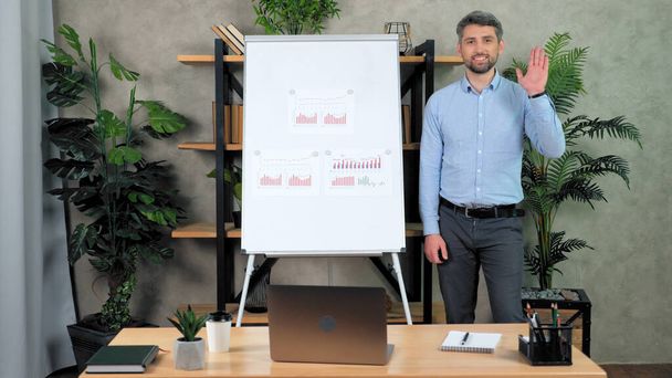 Man teacher stands near flip chart greets speak students remote video call chat - Photo, Image