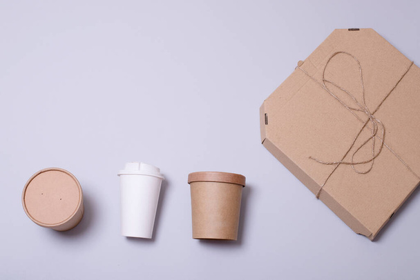 Cardboard containers for food and drinks, pizza box on a gray background with place for text. Top view. Food delivery concept, eco friendly packaging, food to go. Horizontal. Copy space. - Photo, Image
