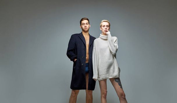 portrait of fashionable slim man and woman in big jacket and sweater on naked body - Foto, Imagen