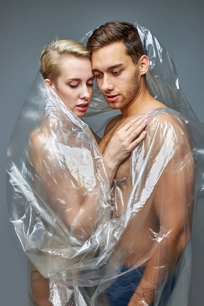 lovely half-naked couple posing wrapped in plastic bag - Valokuva, kuva