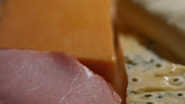 Különböző sós és friss sajtok és sertéssonka előételként vágható, 4K videó - Felvétel, videó