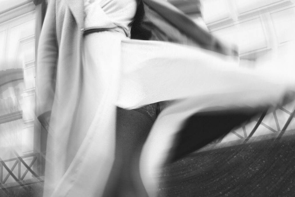 enfoque suave, fotografía borrosa. chica en un abrigo y vestido beige gira en la calle, negro y blanco fot granulado - Foto, imagen