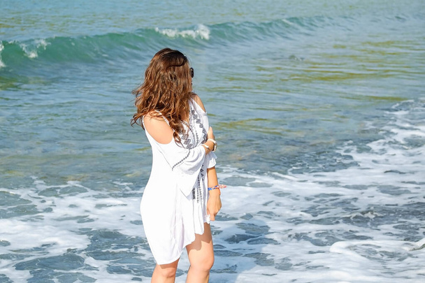 jedna rudowłosa piękna dziewczyna stoi na plaży, seksowna kobieta w ośrodku patrzy na morze, tylna konkurencja - Zdjęcie, obraz