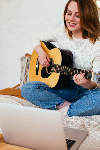 Женщина-блогер снимает себя, играющую на гитаре. Уроки игры на гитаре онлайн - Фото, изображение