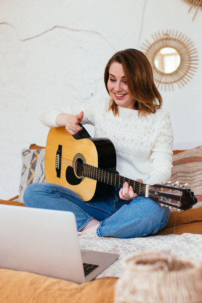 Vrouwelijke vlogger filmt zichzelf terwijl ze gitaar speelt. Gitaarlessen online - Foto, afbeelding