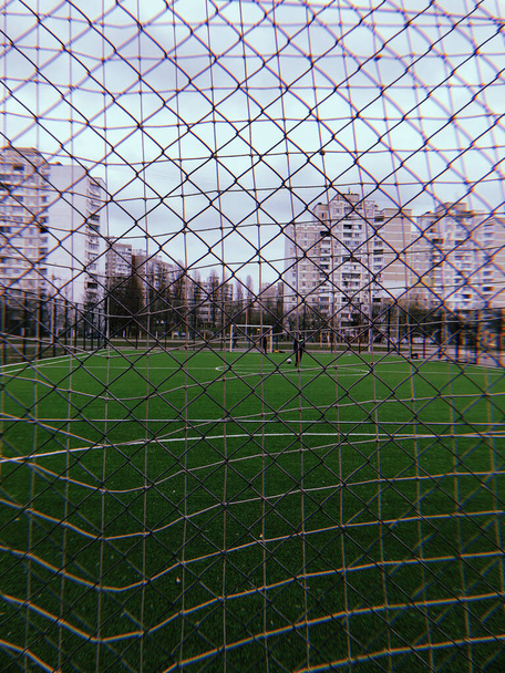 Red de seguridad metálica primer plano de un campo de fútbol, un juego de deportes al aire libre y jugadores de fútbol - Foto, imagen