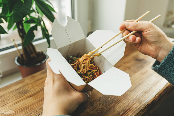 Close-up of noodles in a box. Takeaway food. Person eats food with chopsticks. - Fotó, kép