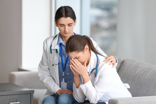Médica mulher acalmando seu colega estressado na clínica - Foto, Imagem