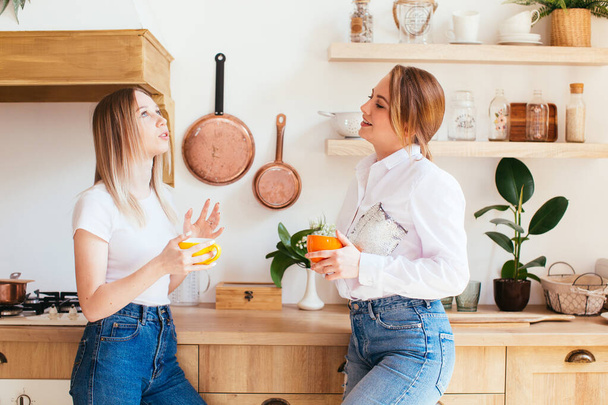 Dwie piękne młode kobiety rozmawiające przy ciepłym drinku w kuchni - Zdjęcie, obraz