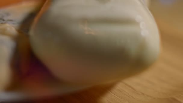 Różne rodzaje słonych i świeżych serów i szynki wieprzowej gotowy do cięcia jako przystawka, wideo 4K. Zdjęcia artystyczne - Materiał filmowy, wideo