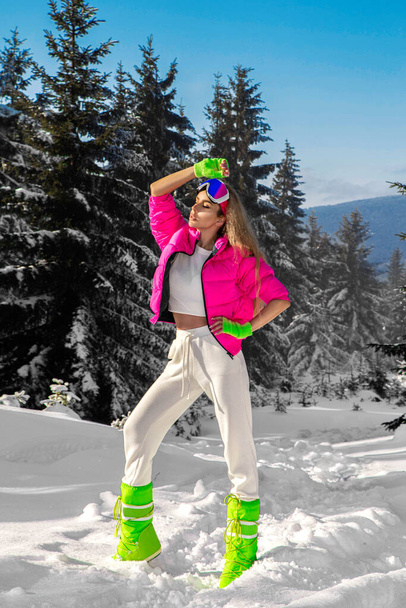 Jonge vrouw winterportret. Wintermodel met skipak en bril. Aantrekkelijke jonge vrouw in de winter buiten. Bergen, witte sneeuw in magische winterdag. - Foto, afbeelding