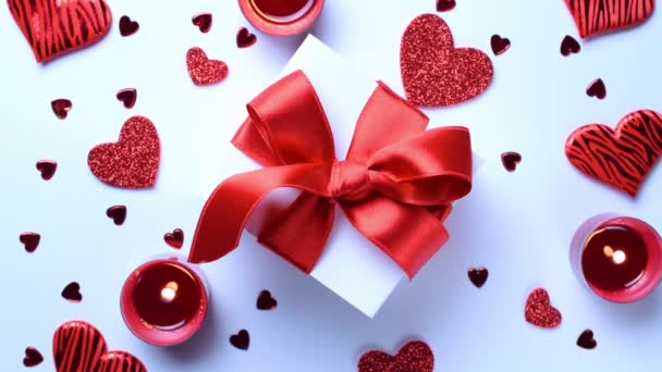 Saint Valentine day: red love hearts, romantic gift box, candle on white background. Romantic message template with copy space. Flat lay, top view, copy space - Footage, Video