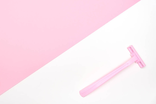 Pink disposable plastic woman razor blade for shaving, body care and unwatred hair removing on legs, armpits and face, flat lay with copy space - 写真・画像