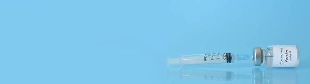 Vacuna en frasco con jeringa sobre fondo azul.El concepto de medicina, salud y ciencia.Vacuna contra el Coronavirus.Espacio para copiar el texto.Banner - Foto, Imagen