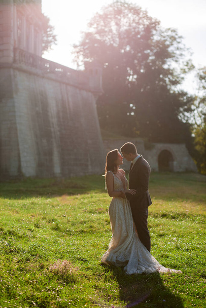 Прекрасная невеста и гум стоят вместе перед старым дворцом. Свадебная пара. Свадебное фото - Фото, изображение