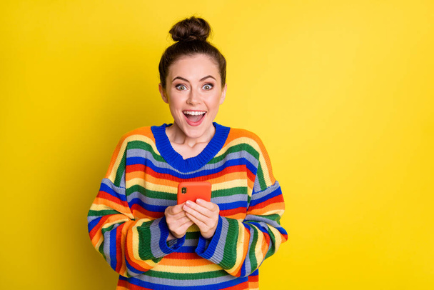 Photo of impressed funny brunette girl hold telephone wear rainbow sweater isolated on bright yellow color background - Foto, immagini