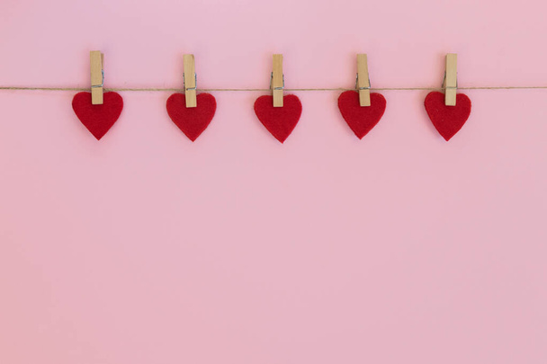 Cuori rossi appesi sulla clothesline su sfondo rosa. Amore, Matrimonio, Romantico e Felice San Valentino concetto di vacanza. - Foto, immagini