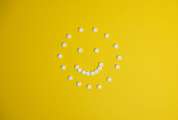 um rosto feito de comprimidos sobre um fundo amarelo - Foto, Imagem