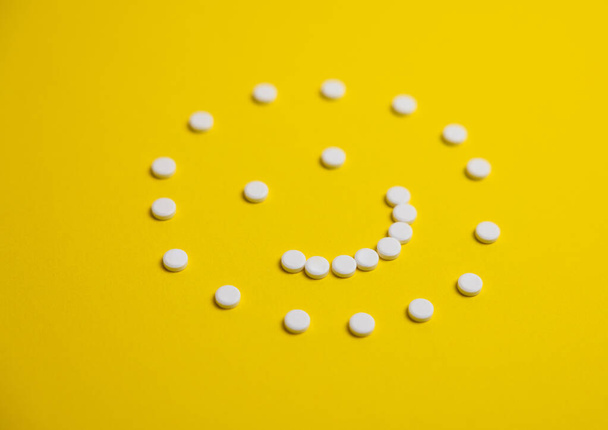 a face made of tablets on a yellow background - Foto, Imagen