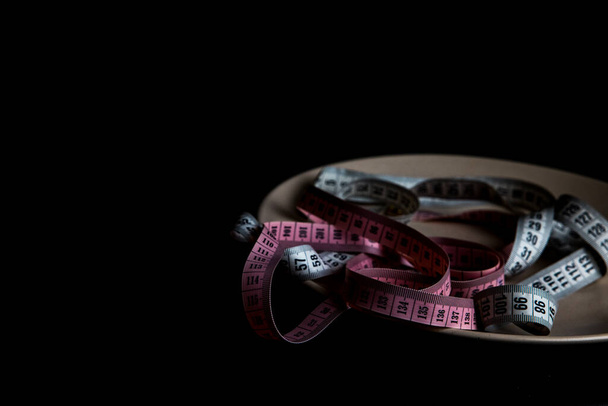 measuring tapes and pills on plate, black background - Photo, Image