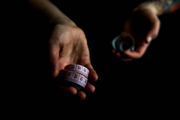 hands holding measuring tapes on black background  - Фото, изображение