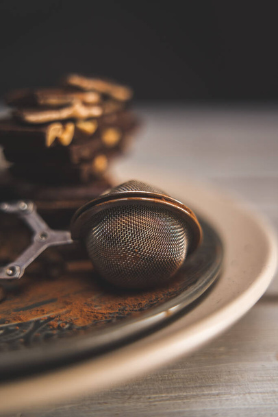 cedník s kakaovým práškem a čokoládou na šedém talíři, dřevěný stůl - Fotografie, Obrázek