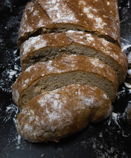 φέτες ψωμί, σιτάρι και αλεύρι σε μαύρο φόντο  - Φωτογραφία, εικόνα