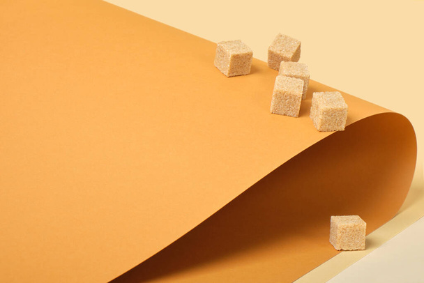 cane sugar cubes on brown background, trend color place copy, roll paper, beige background - Фото, зображення