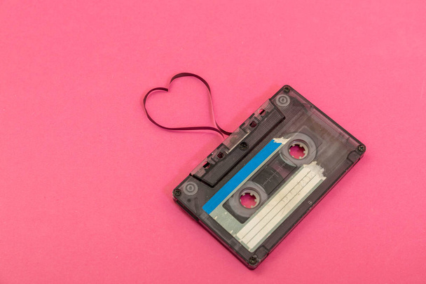 Audio cassette tape on rose backgound. Film shaping heart, Valentine postcard. Empty space. - Foto, afbeelding