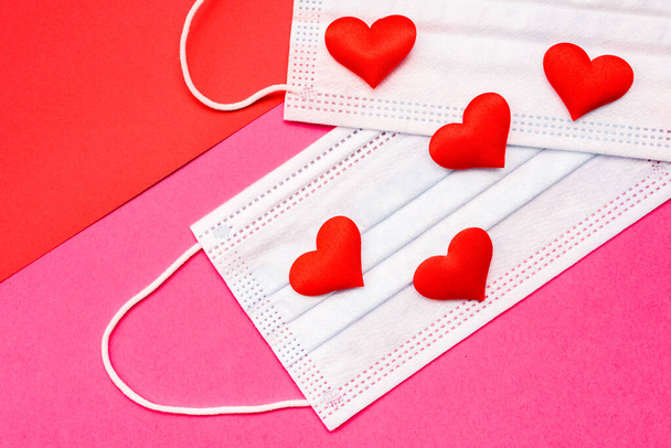 Flat lay of red love hearts on sanitary masks isolated on colored geometric backgrounds. - Photo, Image